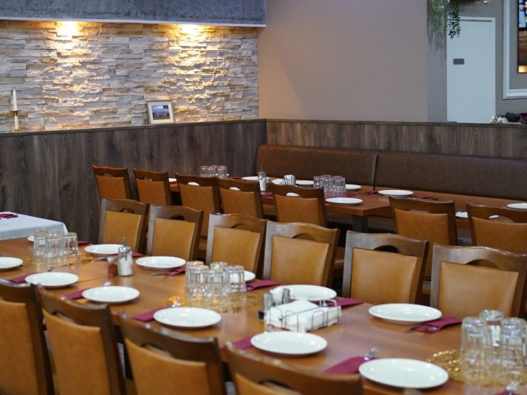 Eine lange, festlich eingedeckte Festtafel mit Holzsessel im elegant gestalteten Innenbereich des Restaurants.